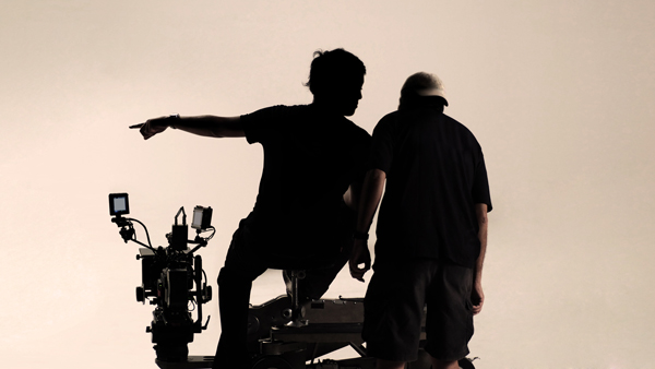 Cameramen silhouettes talking against beige backdrop on set